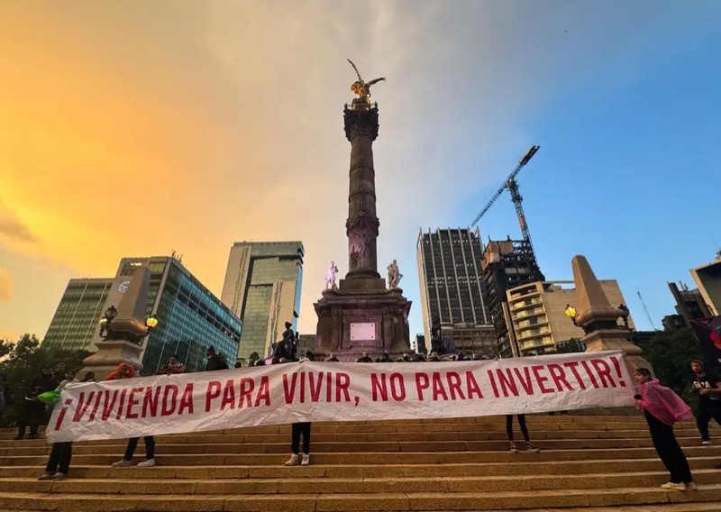 Protest banner reading “¡Vivienda para vivir, no para invertir!” (Housing for living, not for investing!) at the Angel of Independence, Mexico City